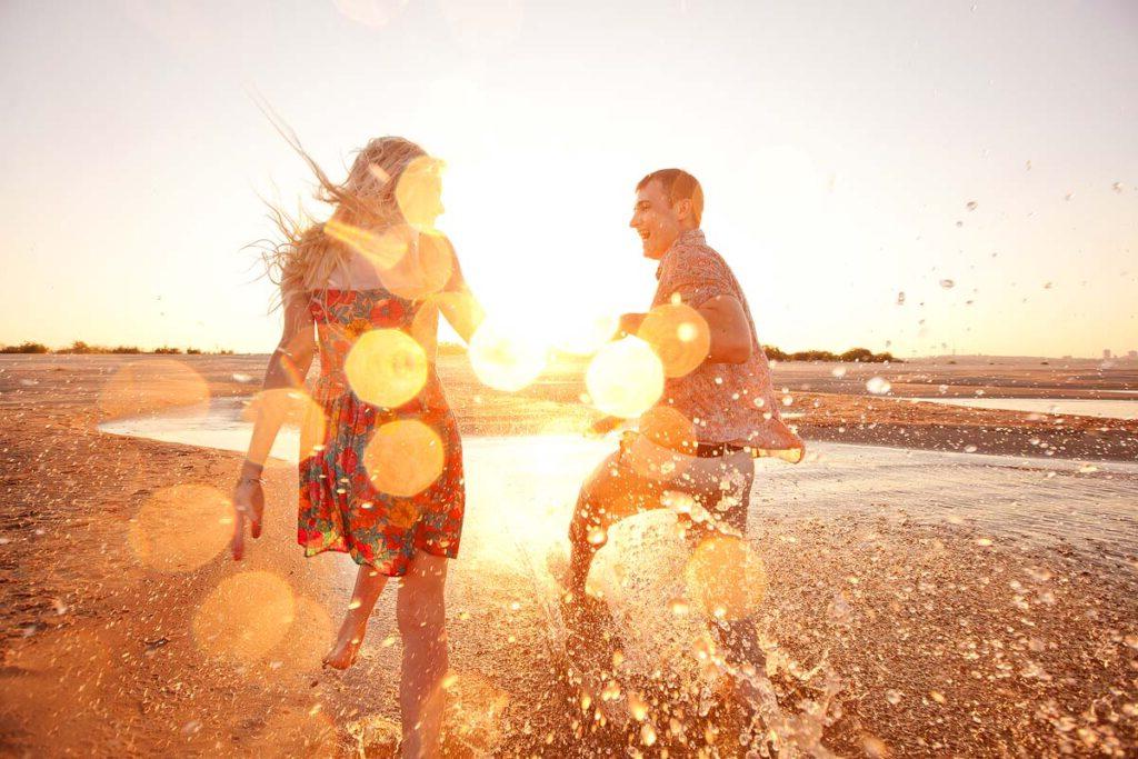 A couple walking on the beach at sunset.