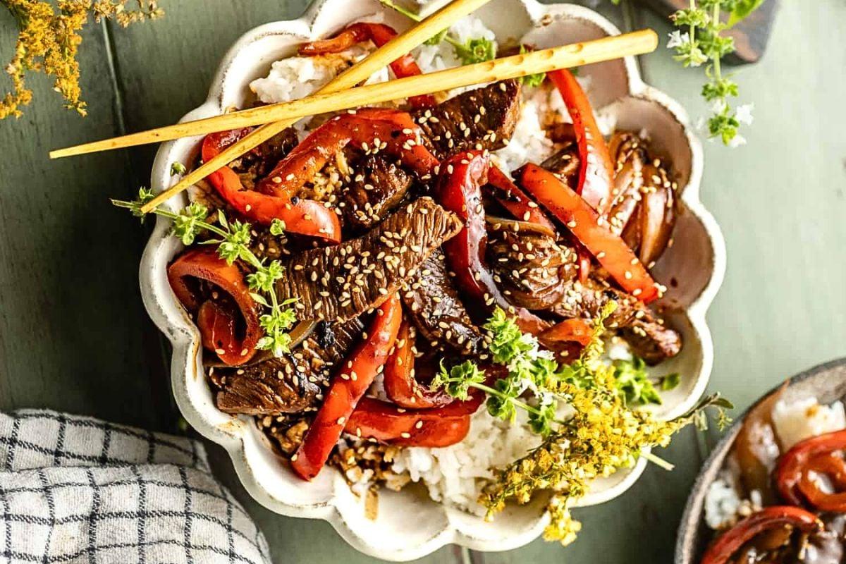 Μοσχαρίσια μπριζόλα με πιπεριές stir fry πάνω από ρύζι, σε μπολ.