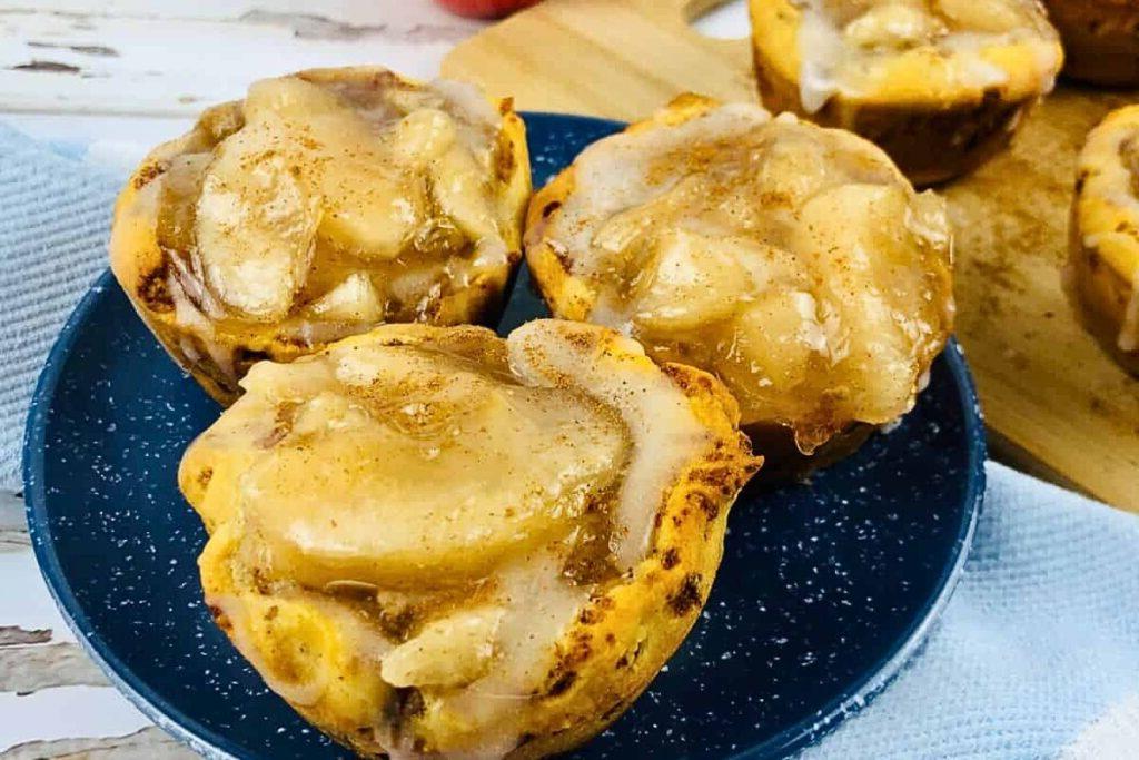 Three cinnamon roll apple pie cups on a plate. 