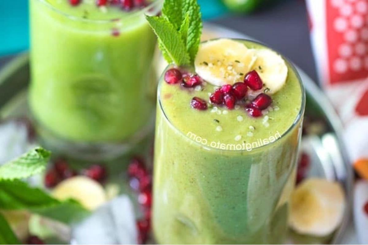 Δύο ποτήρια πράσινου smoothie με συνταγές pinwheel, ρόδι και μπανάνα.