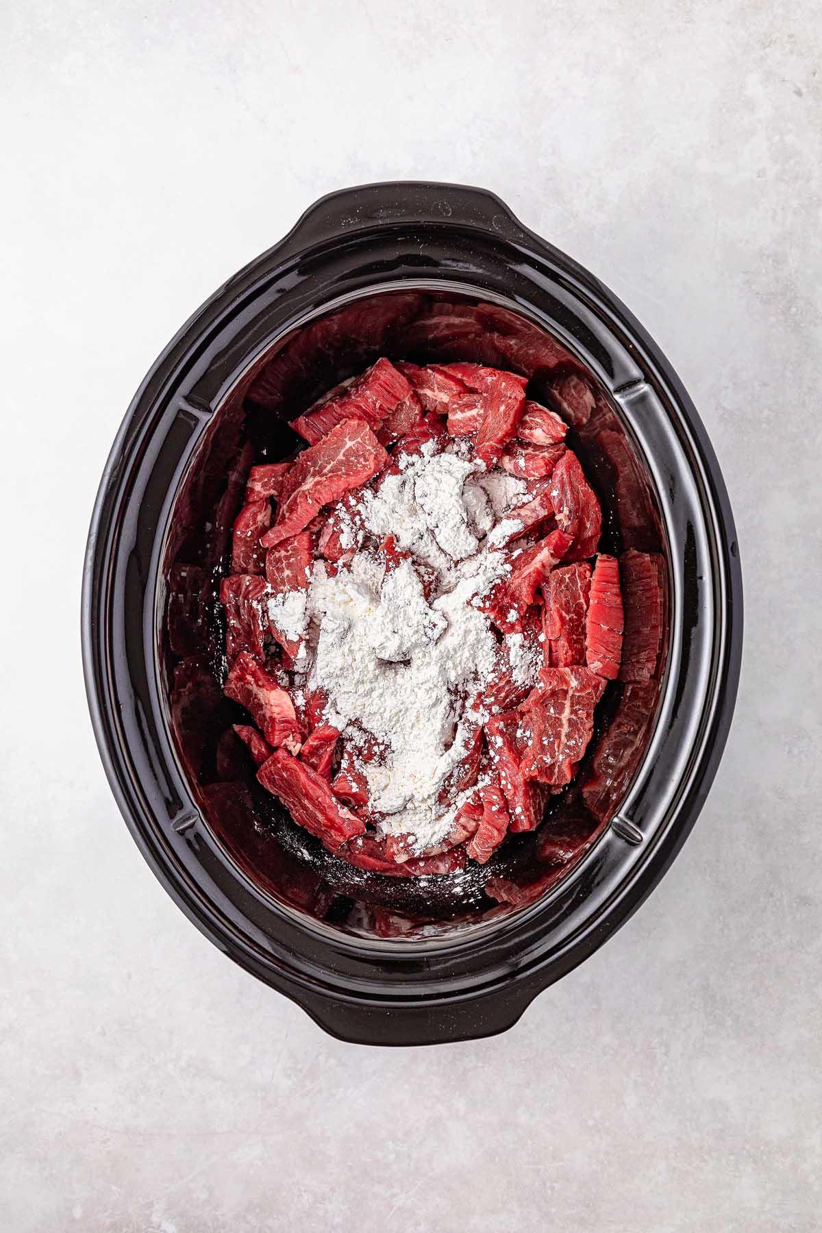 Sliced beef mingles with rich Mongolian seasoning, nestled in the slow cooker, ready for a delicious culinary adventure.