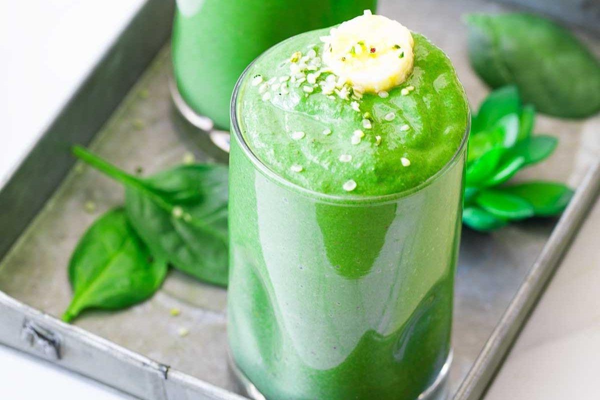 Δύο ποτήρια πράσινου smoothie σε δίσκο με συνταγές pinwheel.