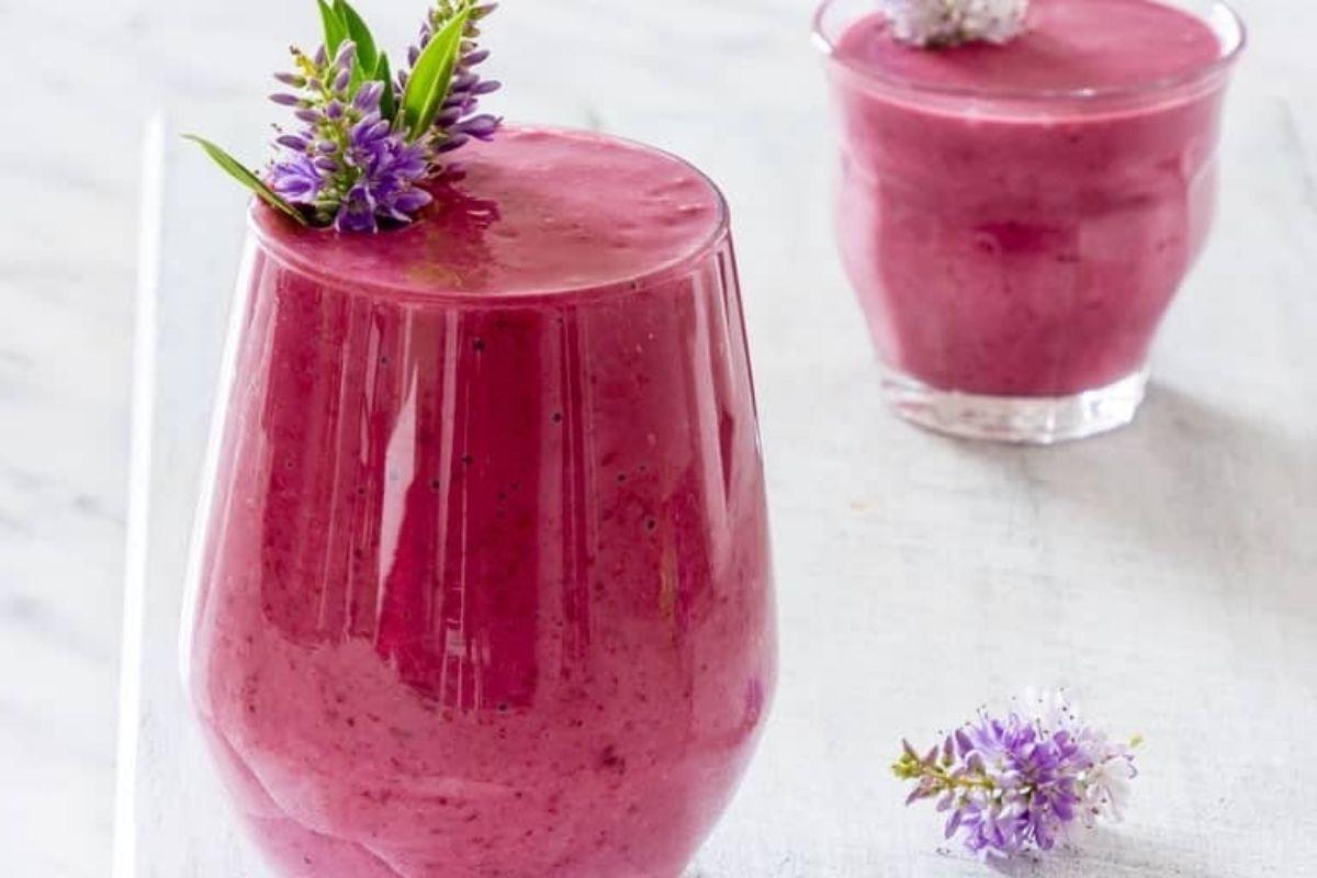 Ένα μωβ smoothie με λουλούδια λεβάντας pinwheel από πάνω.