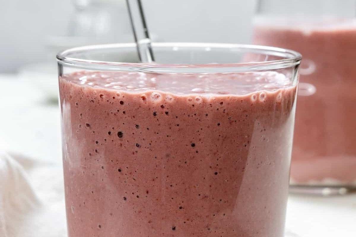 Ένα ποτήρι smoothie φράουλας με καλαμάκι, με συνταγές pinwheel.
