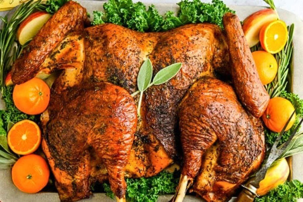 Μια γαλοπούλα spatchcock ψημένη στη σχάρα σε πιατέλα με εσπεριδοειδή.