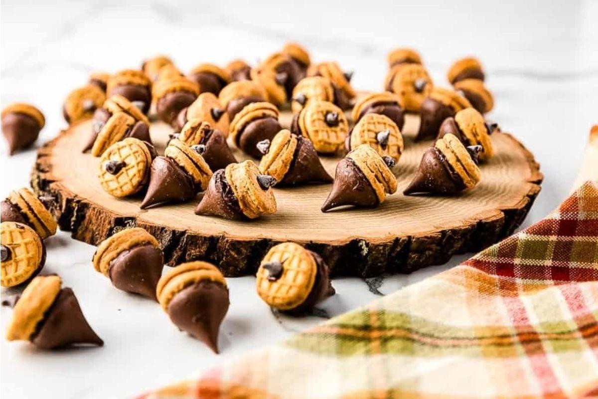 Ένα πιάτο με βελανίδια από συνταγές Hershey Kiss σε ένα ξύλινο κομμάτι κοπής.
