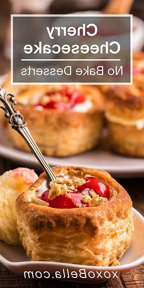 Κοντινό πλάνο ενός από τα ατομικά μας cheesecakes — μια κερασένια τάρτα cheesecake με ένα κουτάλι, γαρνιρισμένη με κεράσια και ψίχουλα, σερβιρισμένη σε ένα πιάτο.