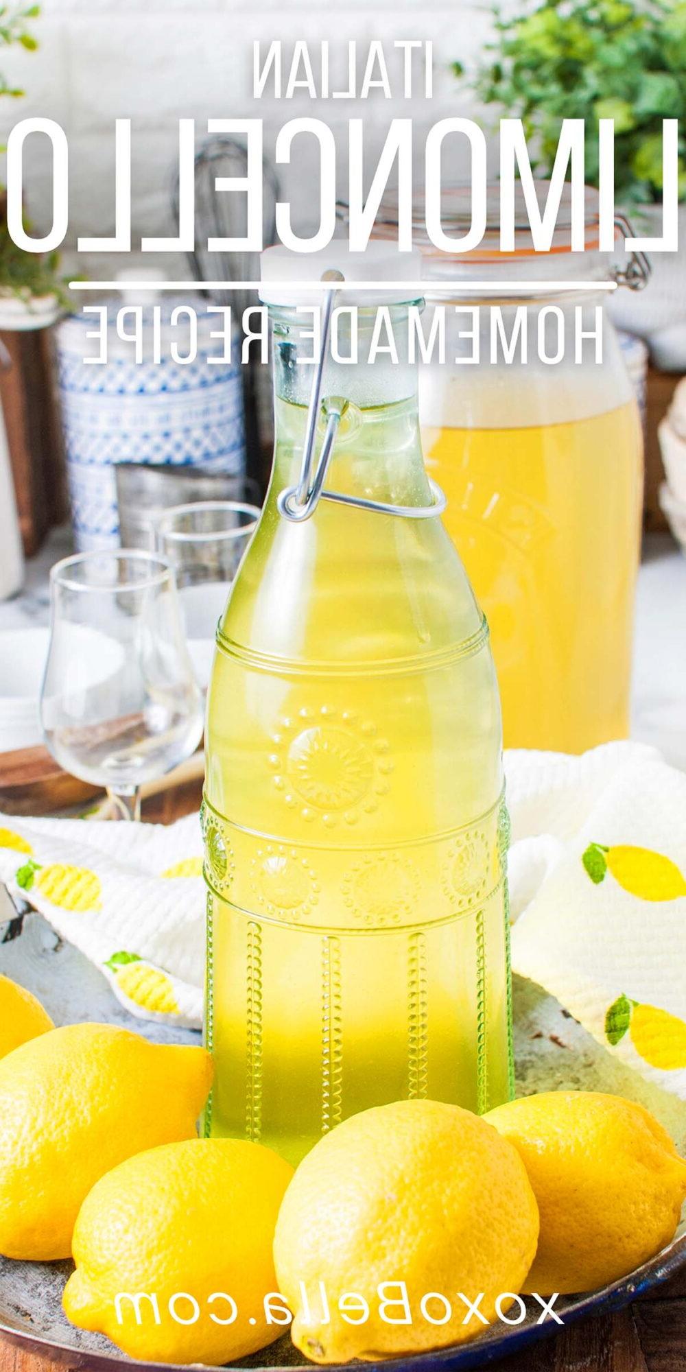 Ένα γυάλινο μπουκάλι σπιτικού limoncello περιβάλλεται από φρέσκα λεμόνια, ενσαρκώνοντας μια αυθεντική ιταλική συνταγή limoncello. Δύο μικρά ποτήρια και ένα μεγαλύτερο βάζο από αυτή τη ζωντανή απόλαυση περιμένουν στο φόντο, έτοιμα να απολαύσουν.