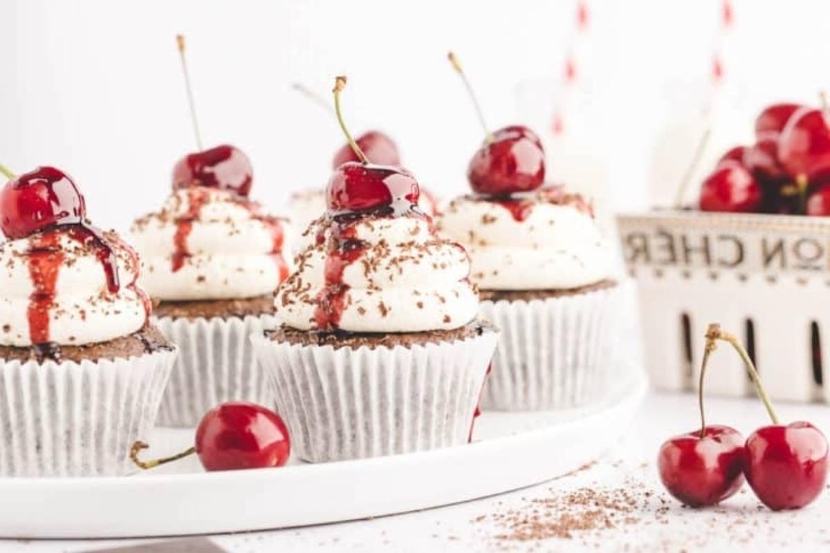 Cupcakes σοκολάτας με κεράσι, σαντιγί και κεράσια σε ένα πιάτο.