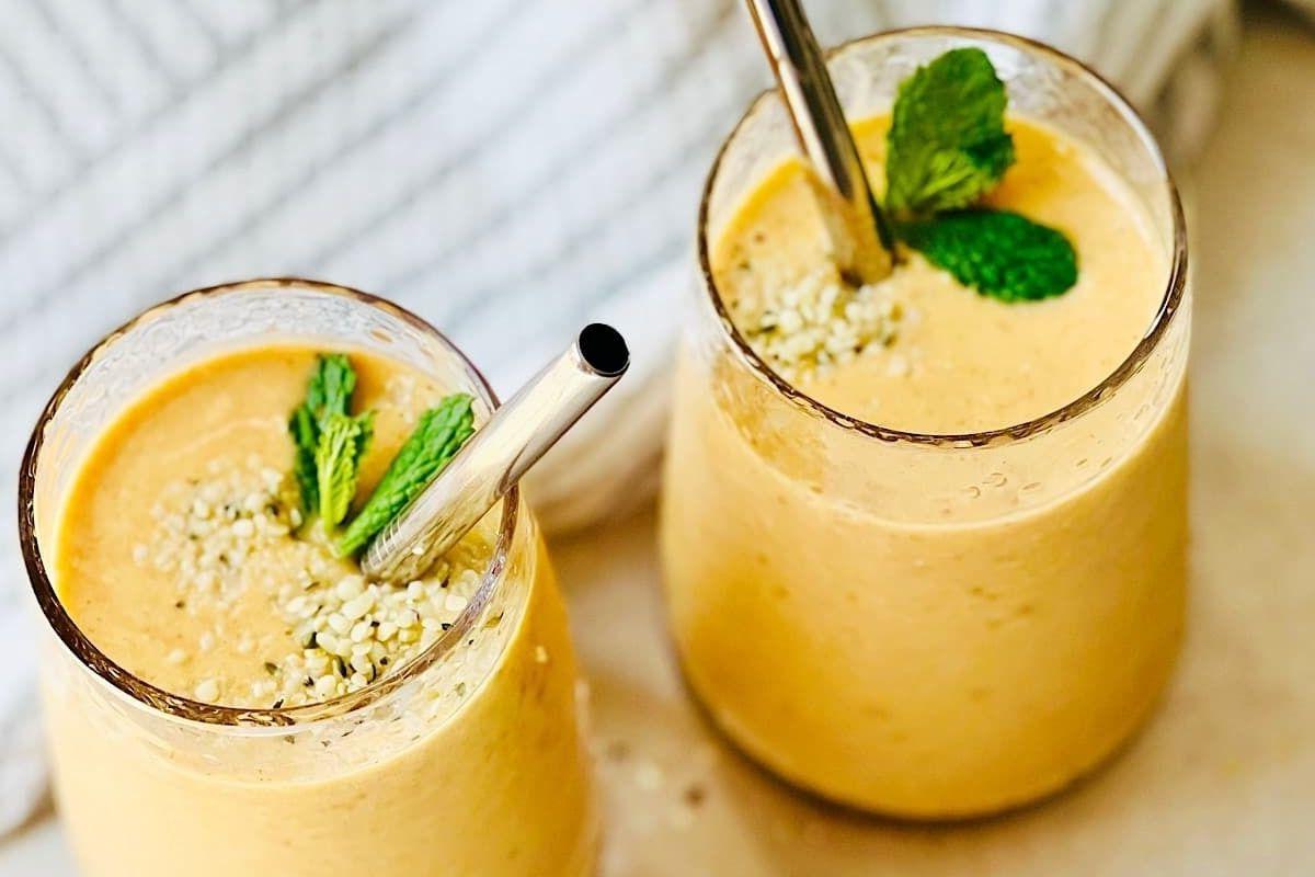 Δύο ποτήρια πορτοκαλί smoothie με φύλλα μέντας και συνταγές pinwheel.