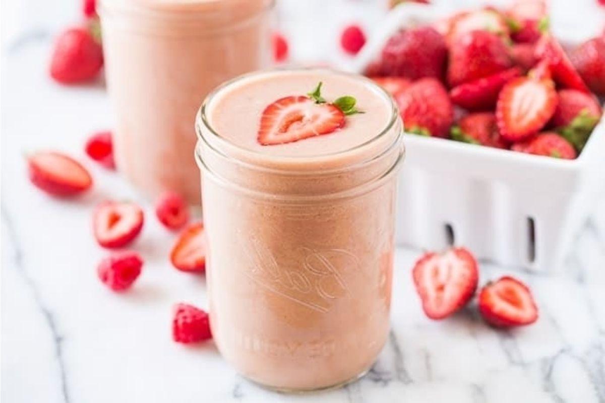 Δύο γυάλινα βάζα γεμάτα smoothies φυστικοβούτυρου και μαρμελάδας φράουλας.