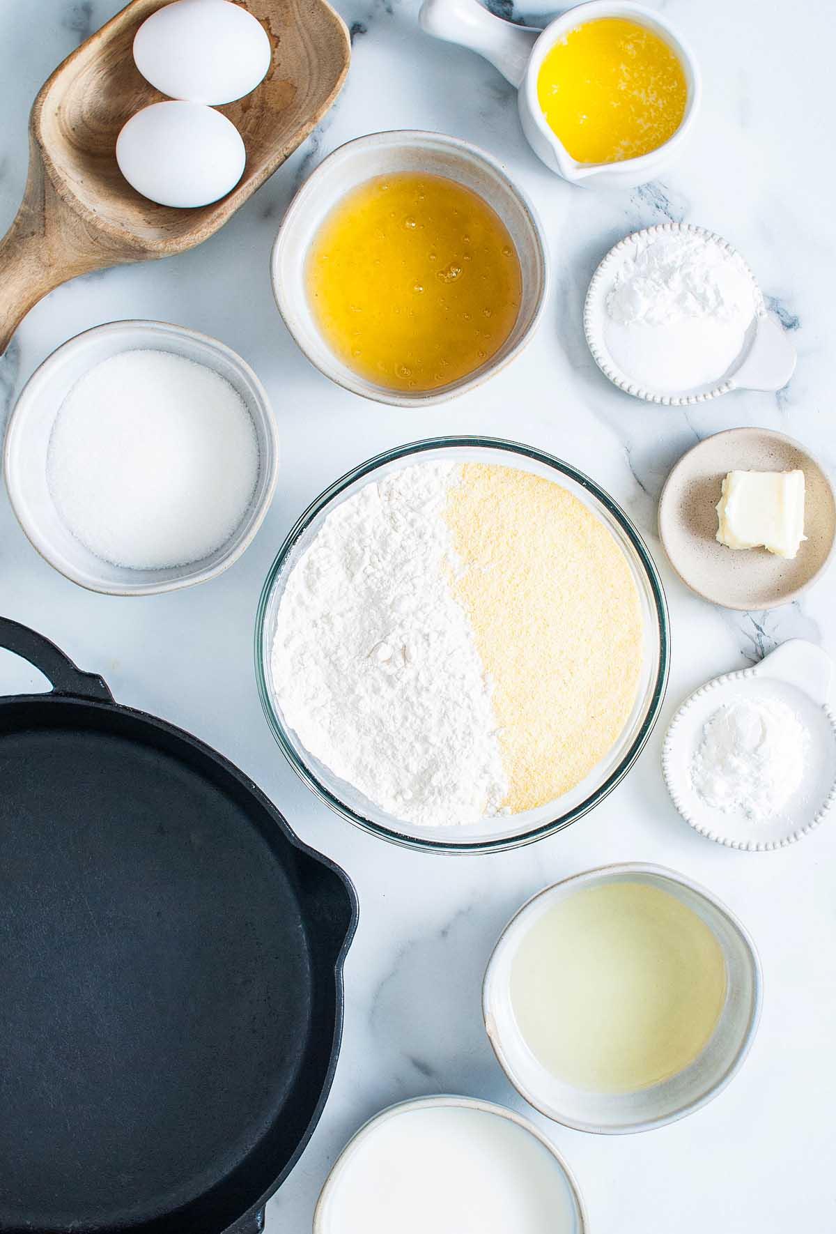 Η συνταγή για ένα γλυκό ψωμί καλαμποκιού σε μαντεμένιο τηγάνι, ψημένο με μέλι, σερβιρισμένο σε μαρμάρινο τραπέζι.
