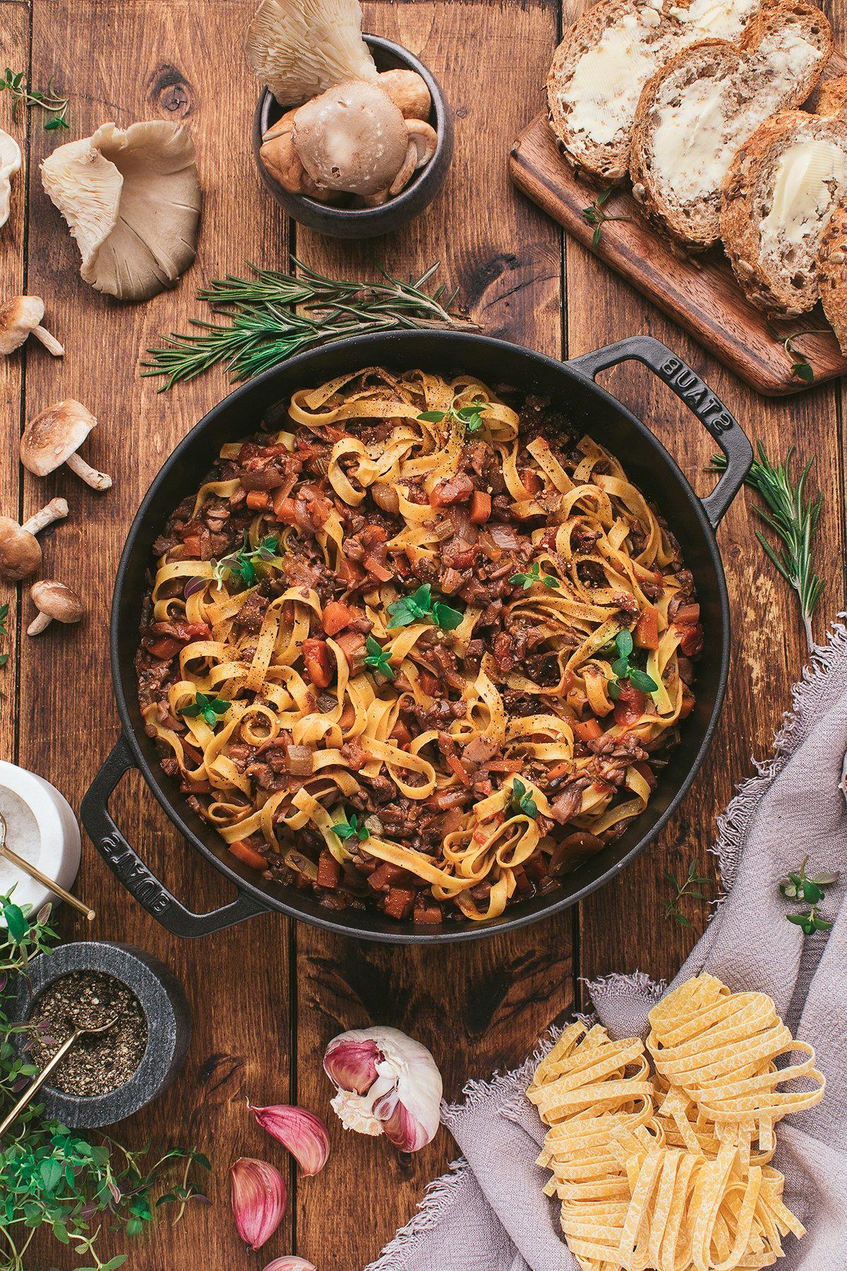 Μαντεμένια κατσαρόλα με ζυμαρικά tagliatelle με πλούσια σπιτική σάλτσα σπαγγέτι με μανιτάρια, περιτριγυρισμένη από ψωμί, μανιτάρια, βότανα, σκόρδο και άψητα ζυμαρικά.