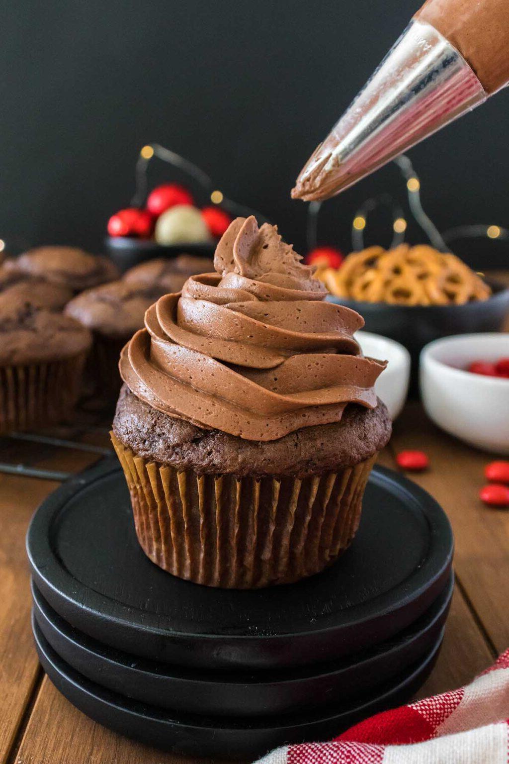 Ένα cupcake ταράνδου γλασάρεται με γλάσο σοκολάτας.