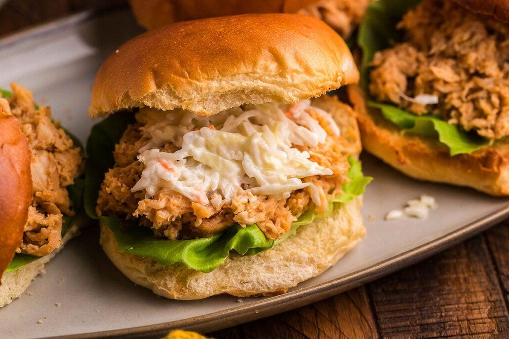Ένα σάντουιτς με pulled chicken και coleslaw σε ένα πιάτο.
