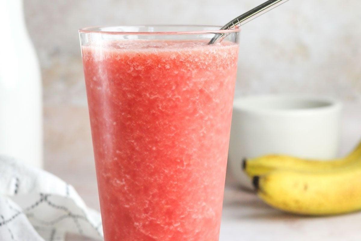 Ένα ποτήρι smoothie καρπουζιού με καλαμάκι, μπανάνες και συνταγές pinwheel.