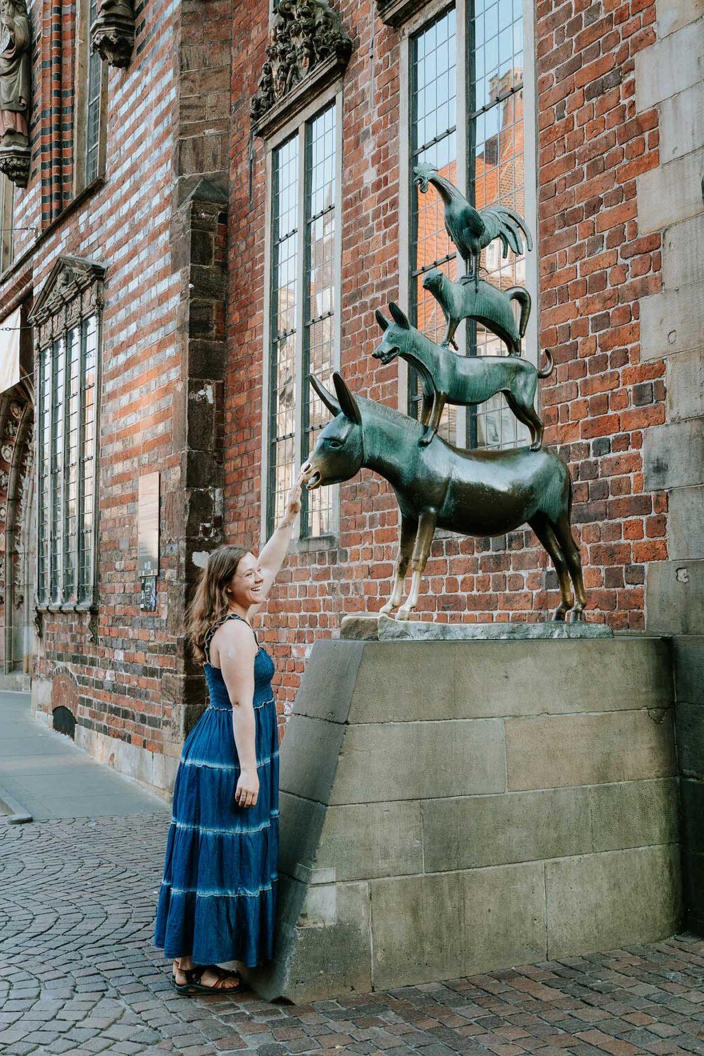 A woman in Bremen touching a statue.