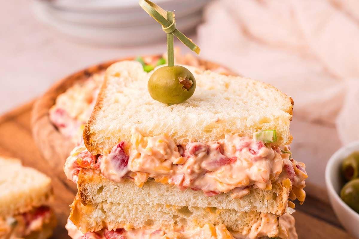 Ένα σάντουιτς με πράσινη ελιά και τυρί pimento από πάνω.