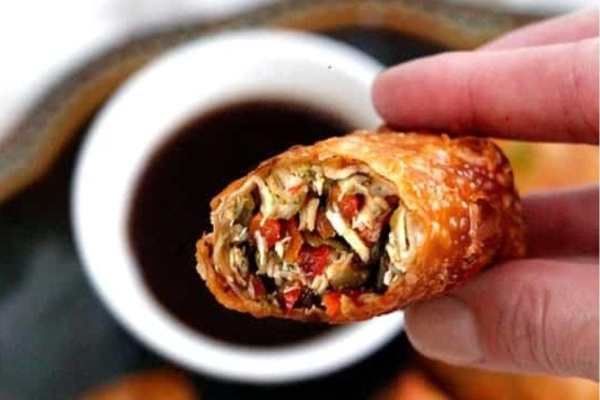 Ένα χέρι που κρατά ένα τραγανό τηγανητό egg roll.