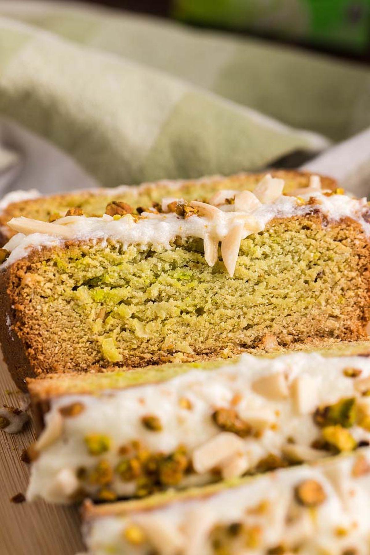 Κοντινό πλάνο από κομμένο Air Fryer Pistachio Coffee Cake με γλάσο και θρυμματισμένα φιστίκια από πάνω.