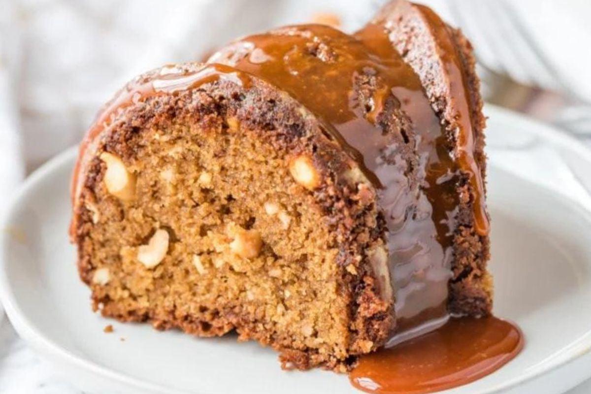 Μια φέτα sticky toffee Bundt cake με σάλτσα καραμέλας σε ένα λευκό πιάτο.