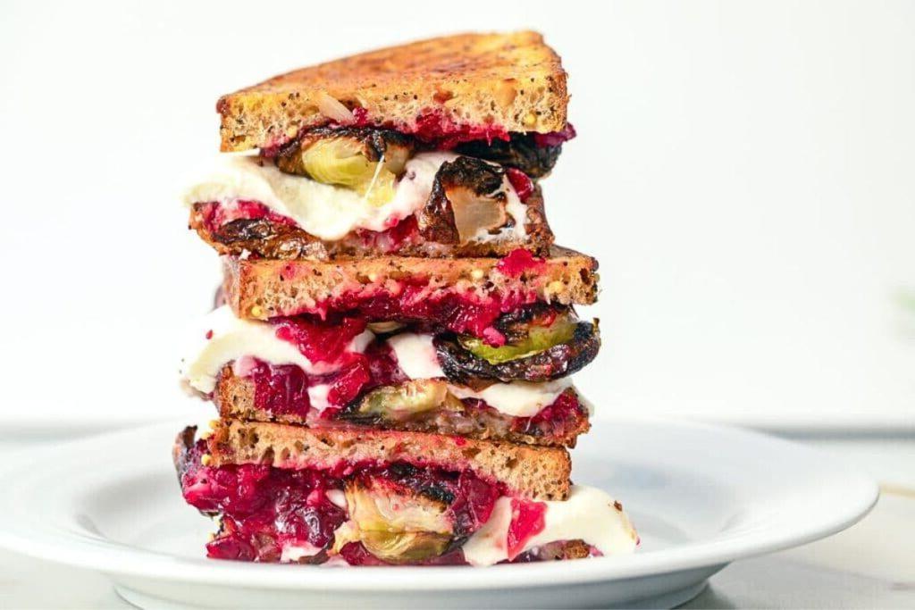 Μια στοίβα από πολύχρωμα σάντουιτς grilled cheese με λαχανάκια Βρυξελλών και κράνμπερι.