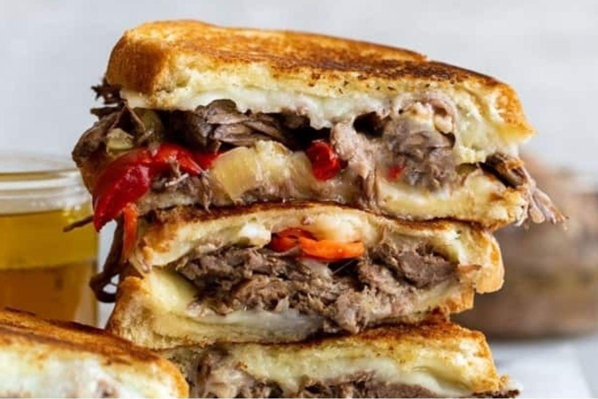 Σάντουιτς grilled cheese γεμιστό με μοσχάρι και λαχανικά, κομμένο στη μέση και στοιβάζονται σε συνταγές με τυρί.