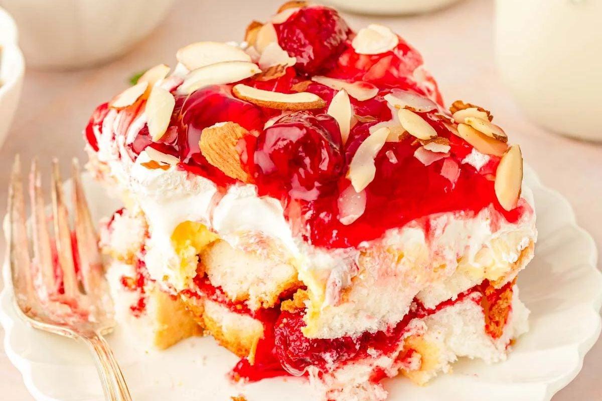 Μια φέτα φραουλένιας shortcake, αγαπημένη ανάμεσα στα πασχαλινά επιδόρπια, με σαντιγί, επικάλυψη φράουλας και ψιλοκομμένα αμύγδαλα.