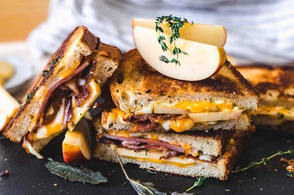 Ένα grilled cheese κομμένο στη μέση σε ένα ξύλο κοπής.
