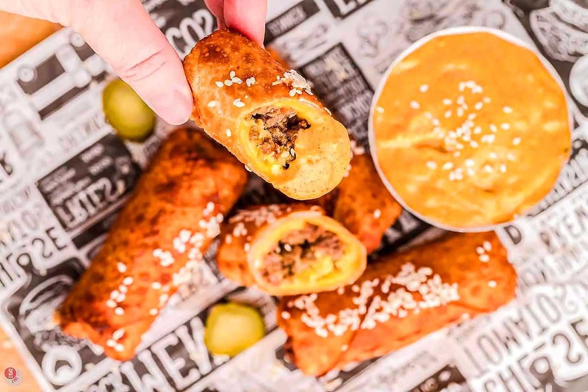 Ένα άτομο βουτά ένα μισοφαγωμένο egg roll με γέμιση κρέατος Big Mac σε μια πλευρική σάλτσα.
