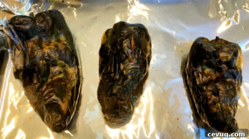 Πιπερότυρο Ντιπ 6 roasted poblano peppers on a baking sheet with tin foil