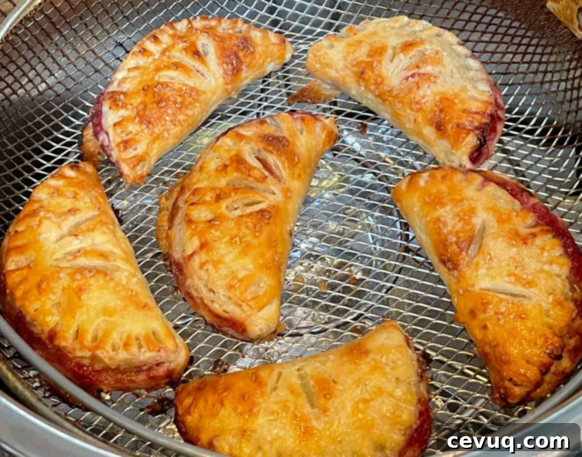 Φλογερές Φράουλες Ανέμου 7 strawberry turnovers in an air fryer basket.