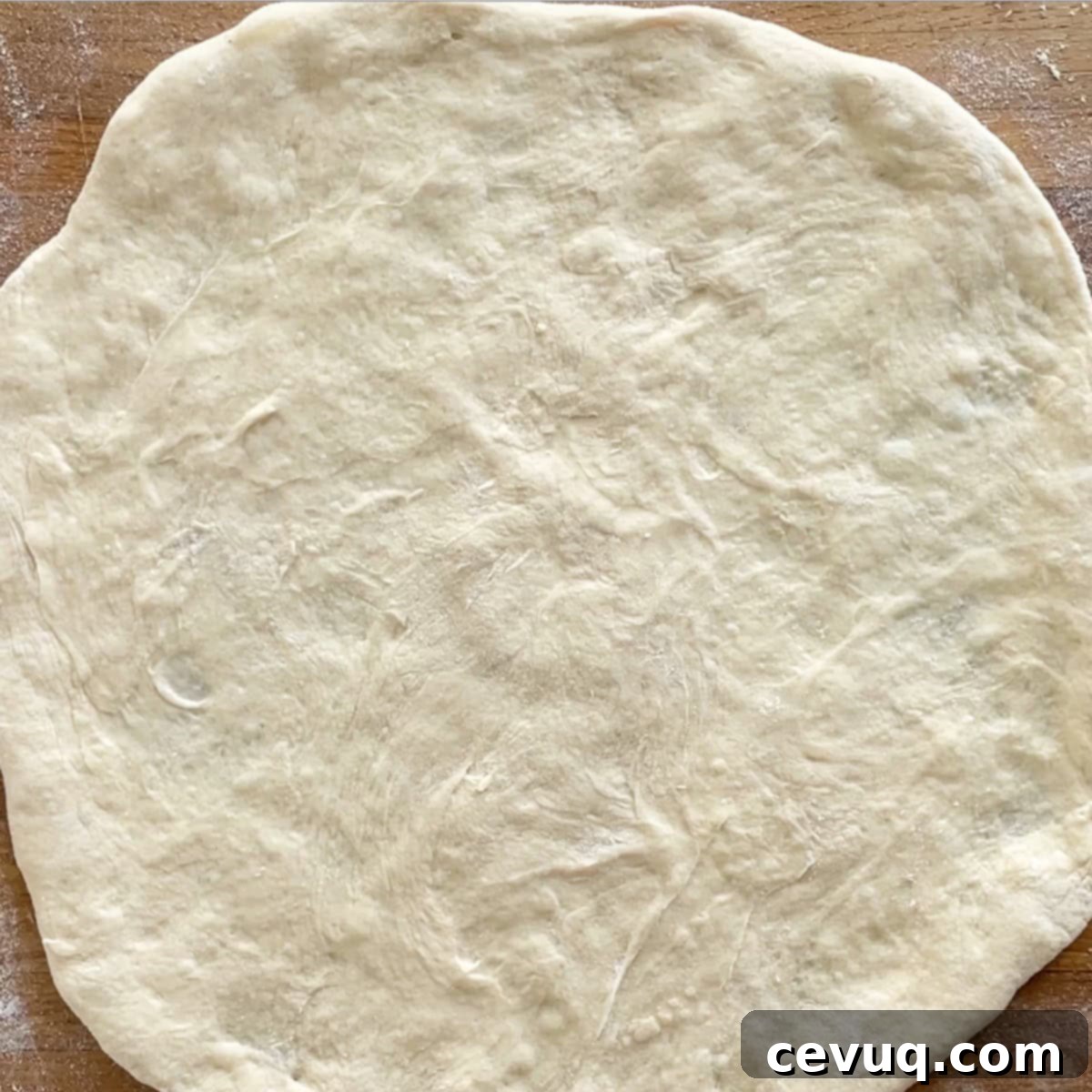 Η Συνταγή για την Απόλυτη Τακό Πίτσα 7 απλωμένη ζύμη πίτσας σε σανίδα κοπής.
