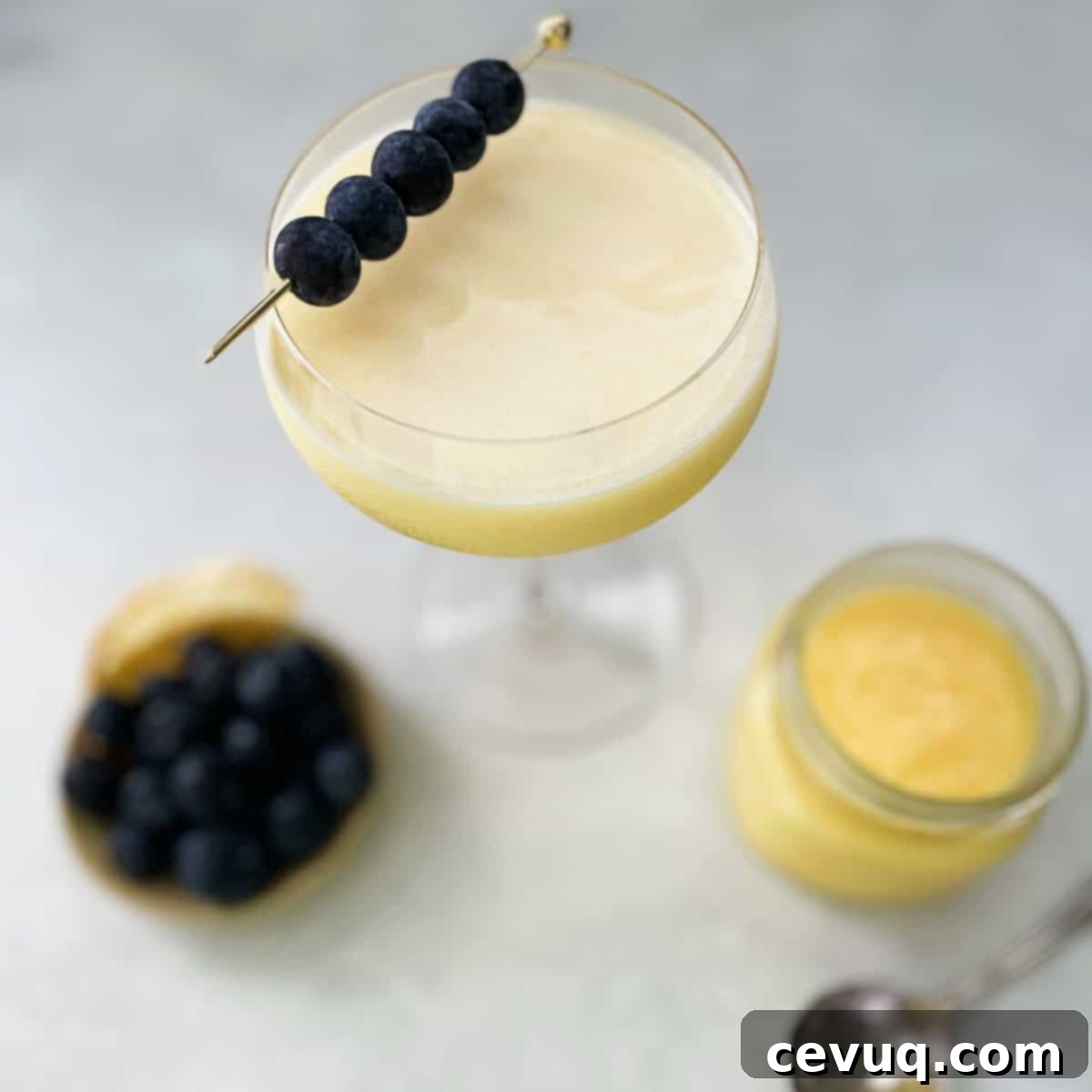 Συνταγή για Κοκτέιλ Λεμονόκρεμας 4 Κοκτέιλ Lemon Curd Martini γαρνιρισμένο με ένα βατόμουρο, σερβιρισμένο σε ποτήρι martini.