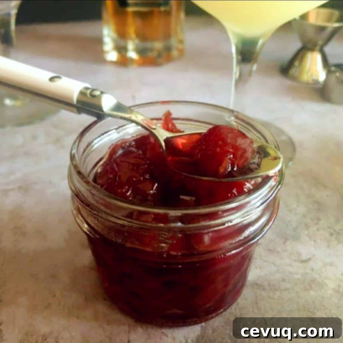 Συνταγή Βύσσινου Αμαρένα 2 amarena cocktail cherries in a jar with a spoon.