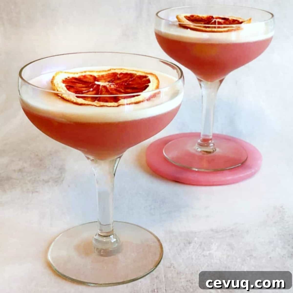 Σαγκουίνι Πίσκο Σάουρ 2 Ένα ποτήρι Blood Orange Pisco Sour κοκτέιλ με φέτες αιματόπορτου για γαρνιτούρα και φόντο ένα ξύλινο τραπέζι.