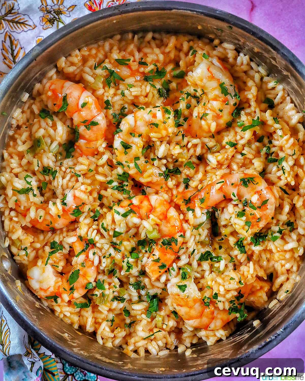risotto with prawns and herbs in a stainless steel pan.