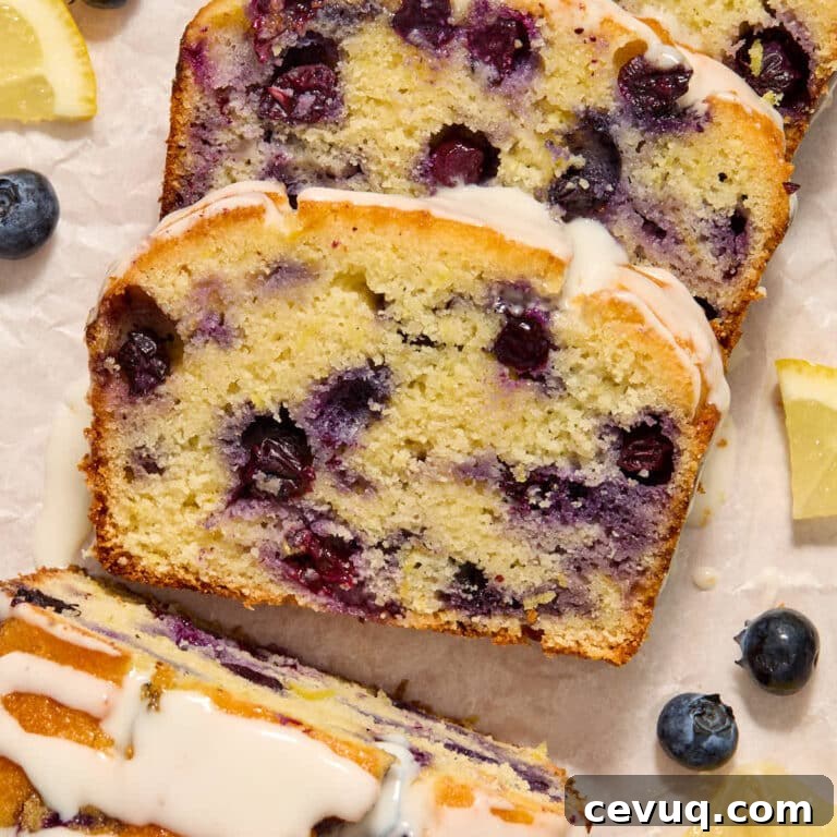 Slices of almond flour lemon blueberry bread topped with glaze and arranged on white parchment paper.