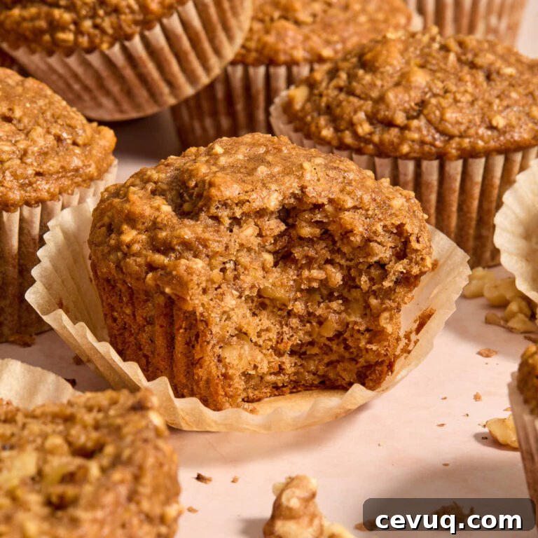 Side view of banana nut muffins with one on a parchment liner and a bite removed.