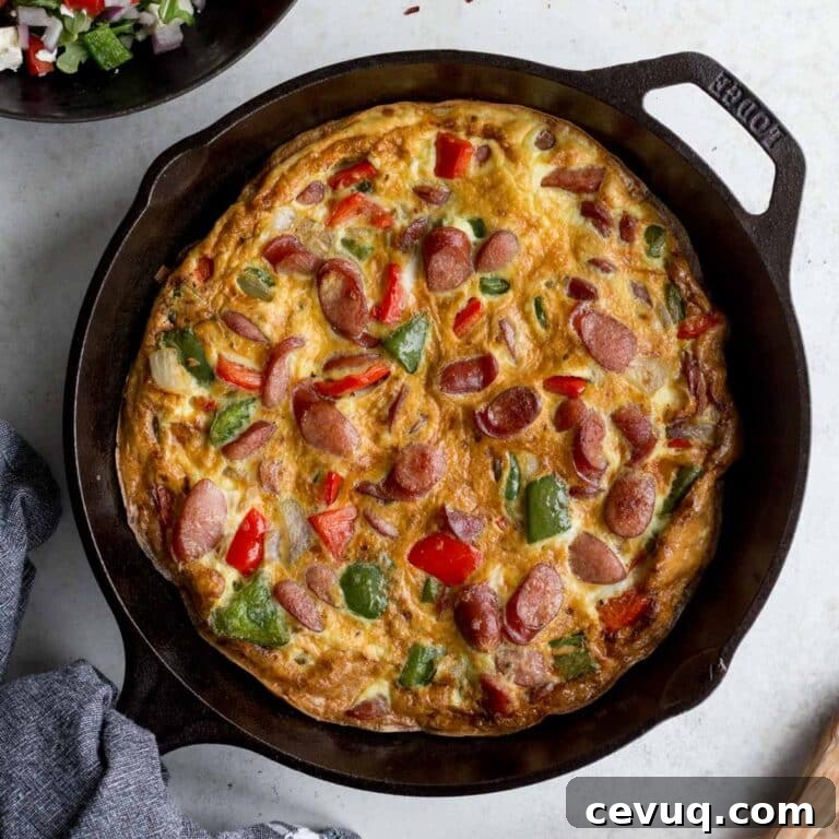 Sausage frittata with peppers and onions in a black cast iron skillet.