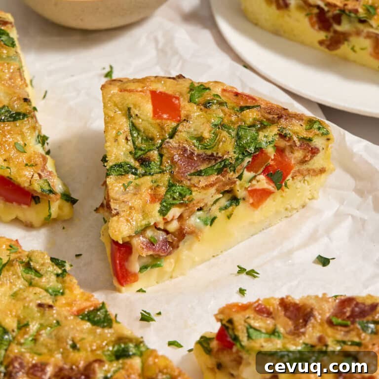 Close up view of a slice of air fryer frittata on white parchment paper.