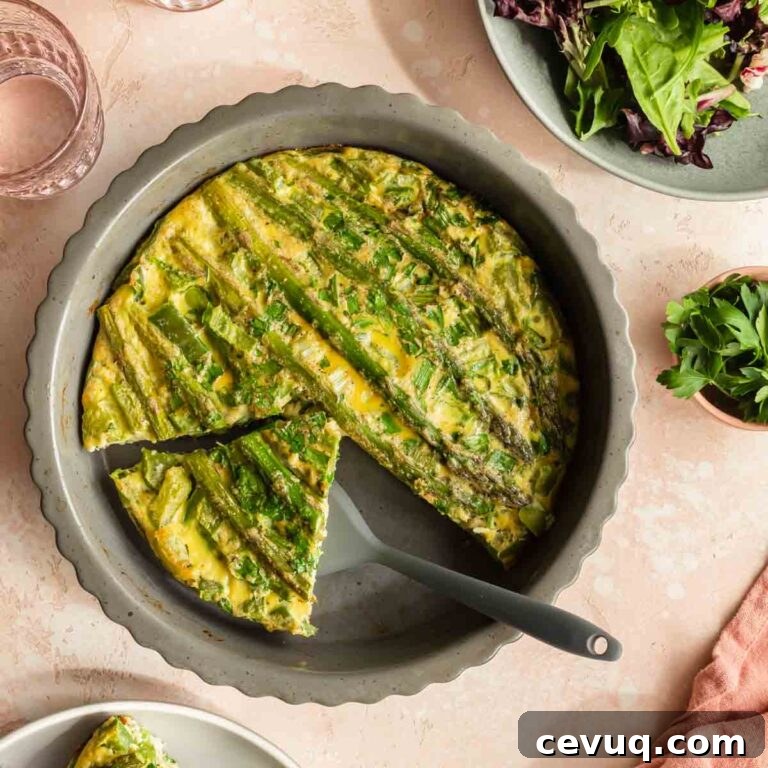 Overhead view of asparagus crustless quiche in a dish with a piece being removed.
