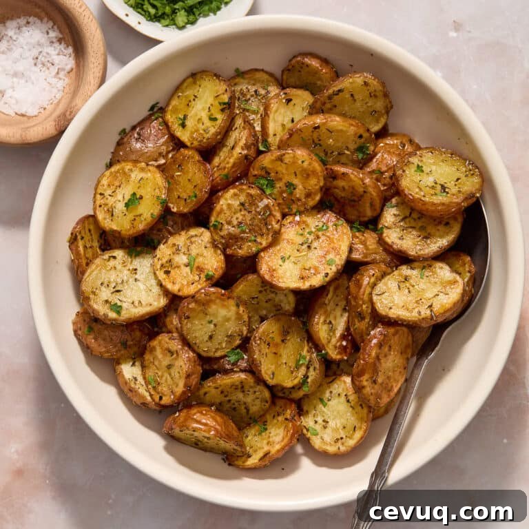 Air fryer baby potatoes served in a white bowl and topped with sea salt and chopped fresh parsley.