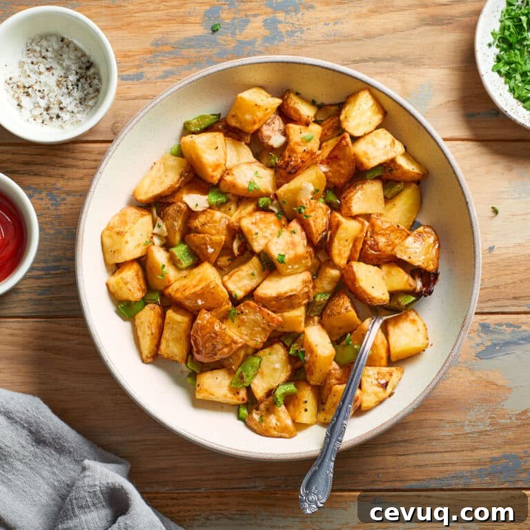 Air fryer home fries in a bowl with a spoon inserted into it.