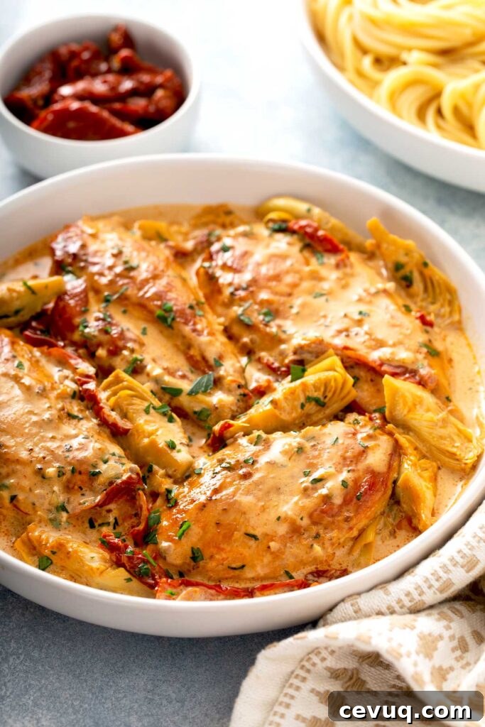 Creamy Sun-Dried Tomato Chicken with Garlic and Herbs 2 Chicken breast in a creamy sauce made with sun dried tomatoes and artichokes on a white bowl