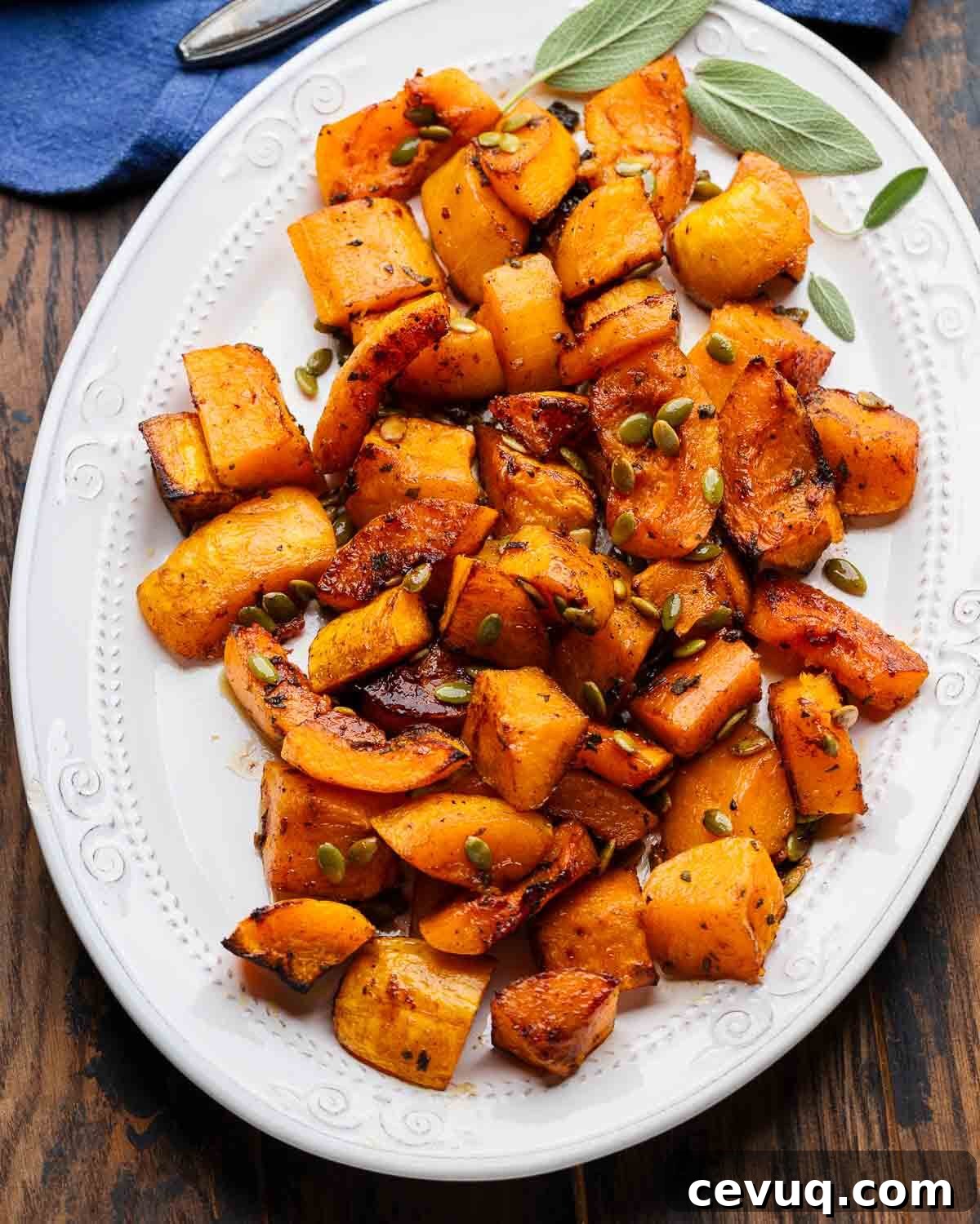Cinnamon roasted butternut squash on white platter with sage garnish.