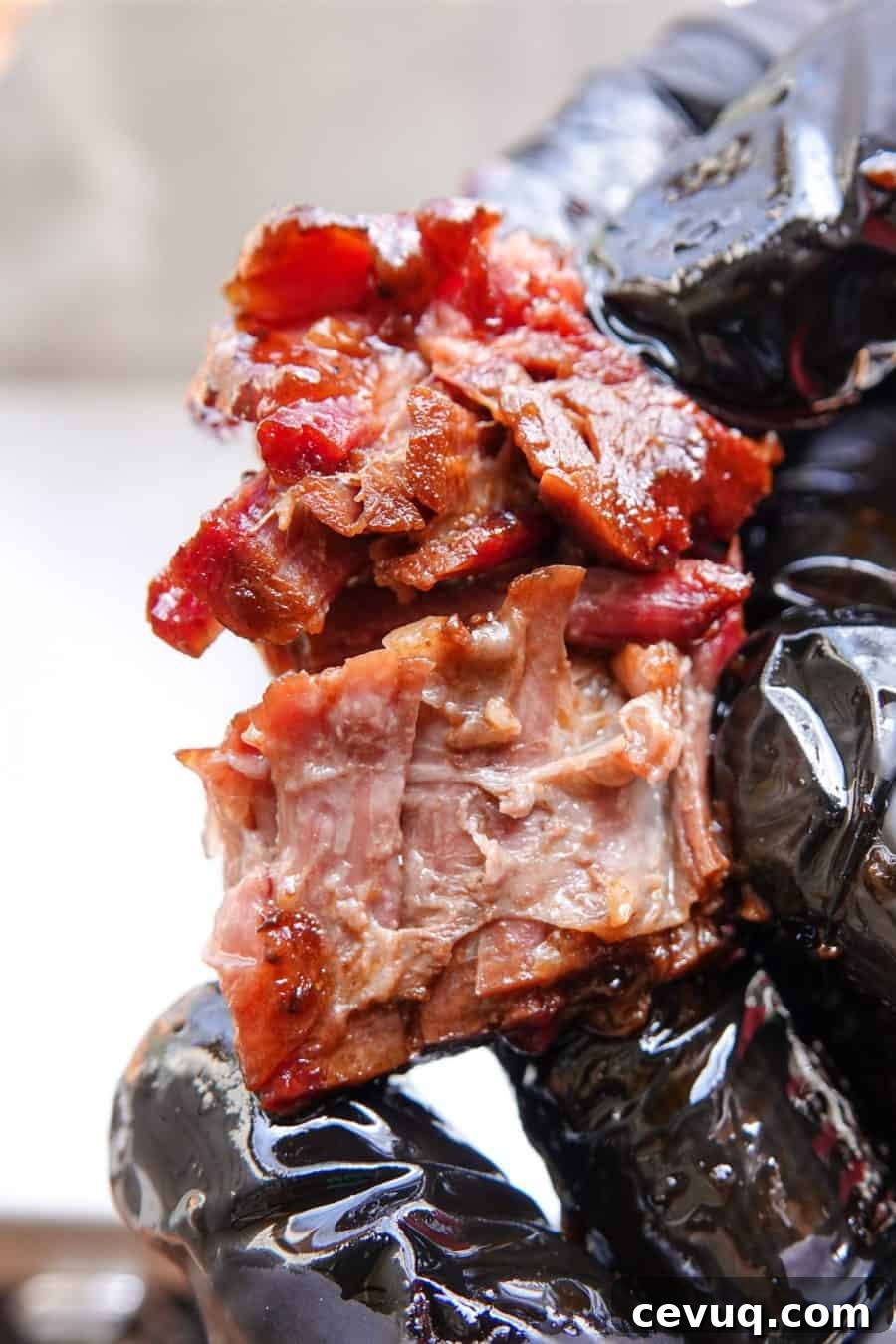 Smoked burnt end being ripped in half with black gloves