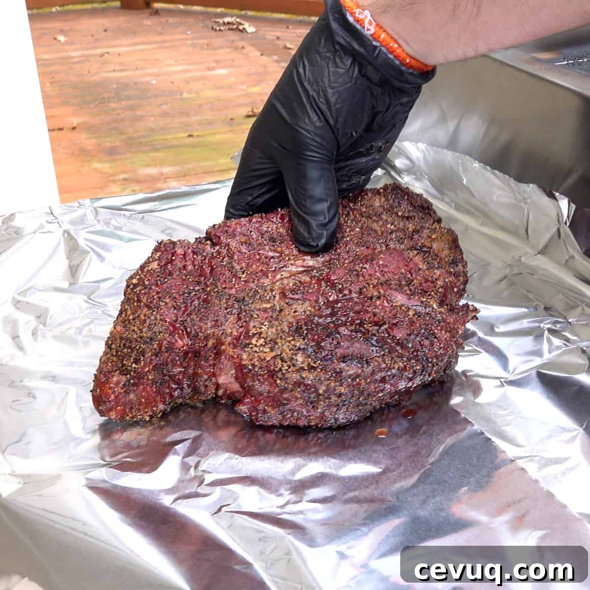 Smoked chuck roast being placed on aluminum foil