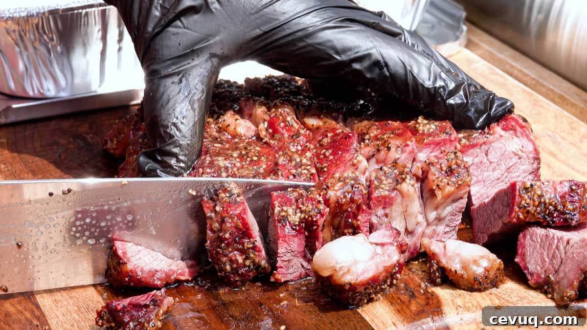 Slicing smoked chuck roast into small pieces on cutting board for burnt ends