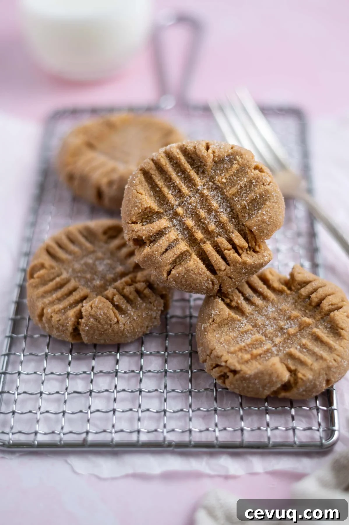 four cookies on a cooling rack with a fork and milk in the background